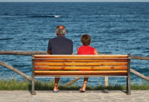 parenting - father and son sitting on a bench and looking at the water