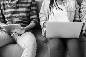 two people sitting next to each other with laptops